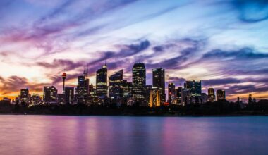 lighted city buildings near body of water under cloudy sky